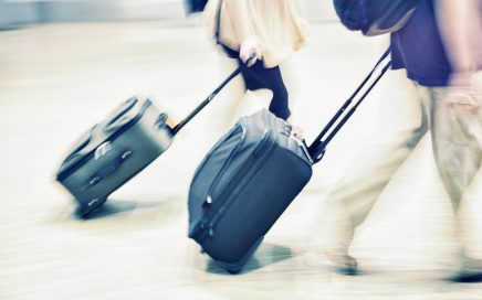 Couple walking with suitcases having asked can you take a razor in hand luggage?